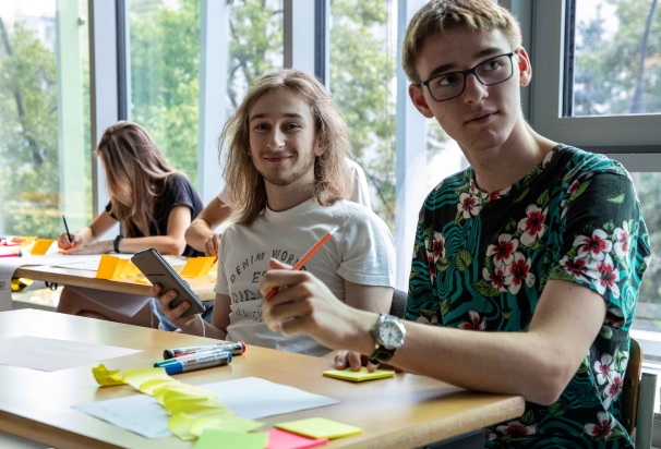 Dwóch chłopaków siedzi w ławce i rozwiązują zadania.
